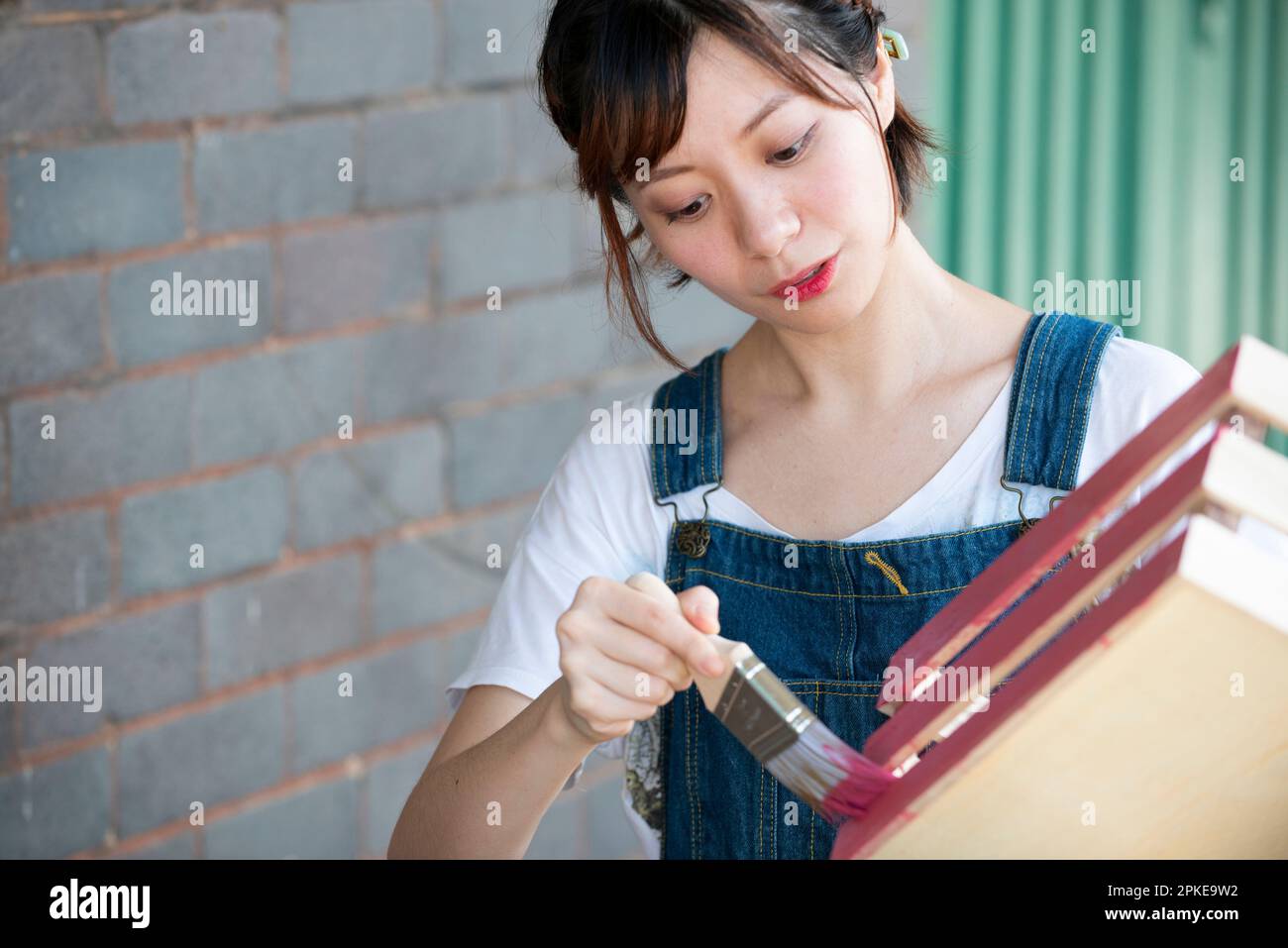 Mujer pintando una caja con un pincel Foto de stock