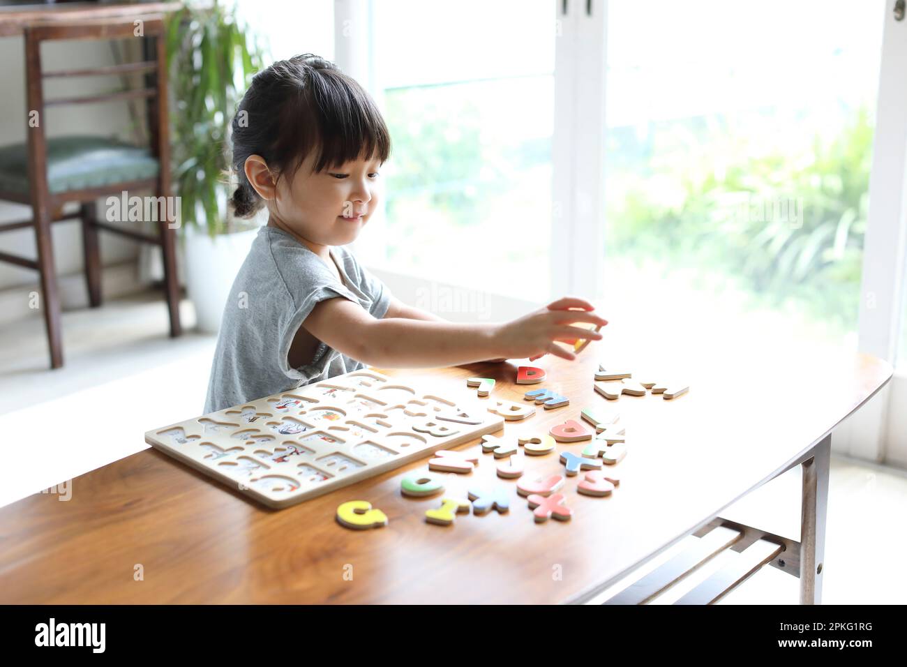 Muchacha jugando con rompecabezas del alfabeto Foto de stock