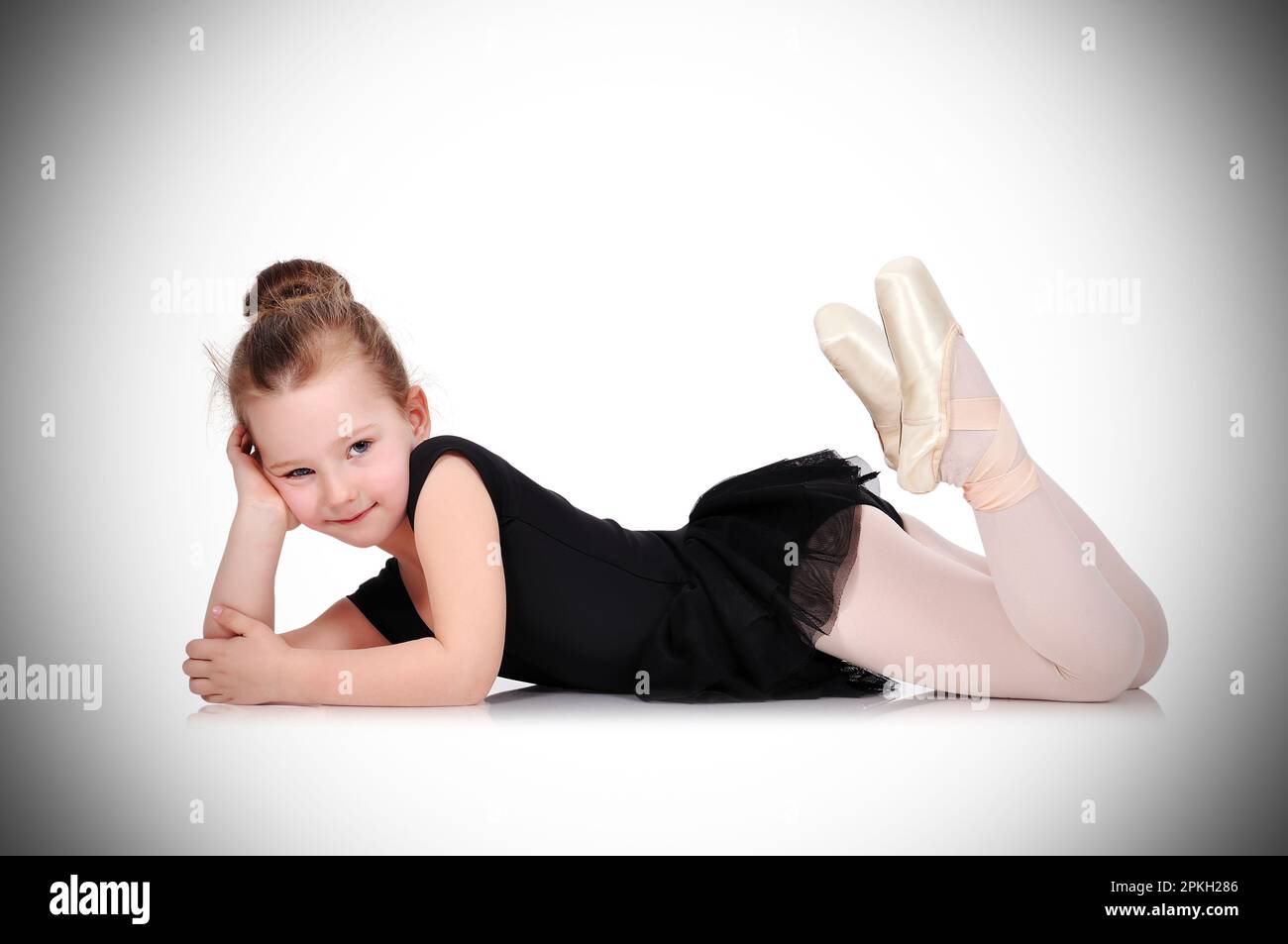 Una niñita linda con un disfraz de bailarina con una máquina de ballet en  un fondo blanco