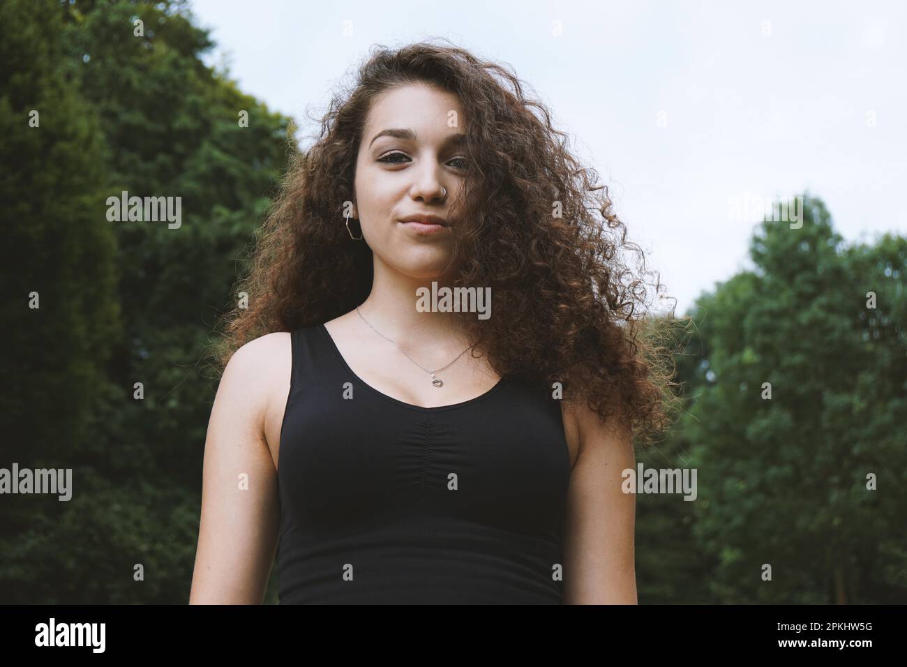 Retrato de una mujer joven hermosa con el pelo rizado largo morena en la naturaleza Foto de stock