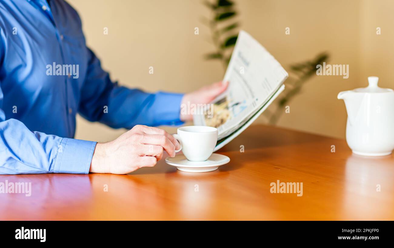 Un Best Ager es beber café y leer un periódico. Foto de stock