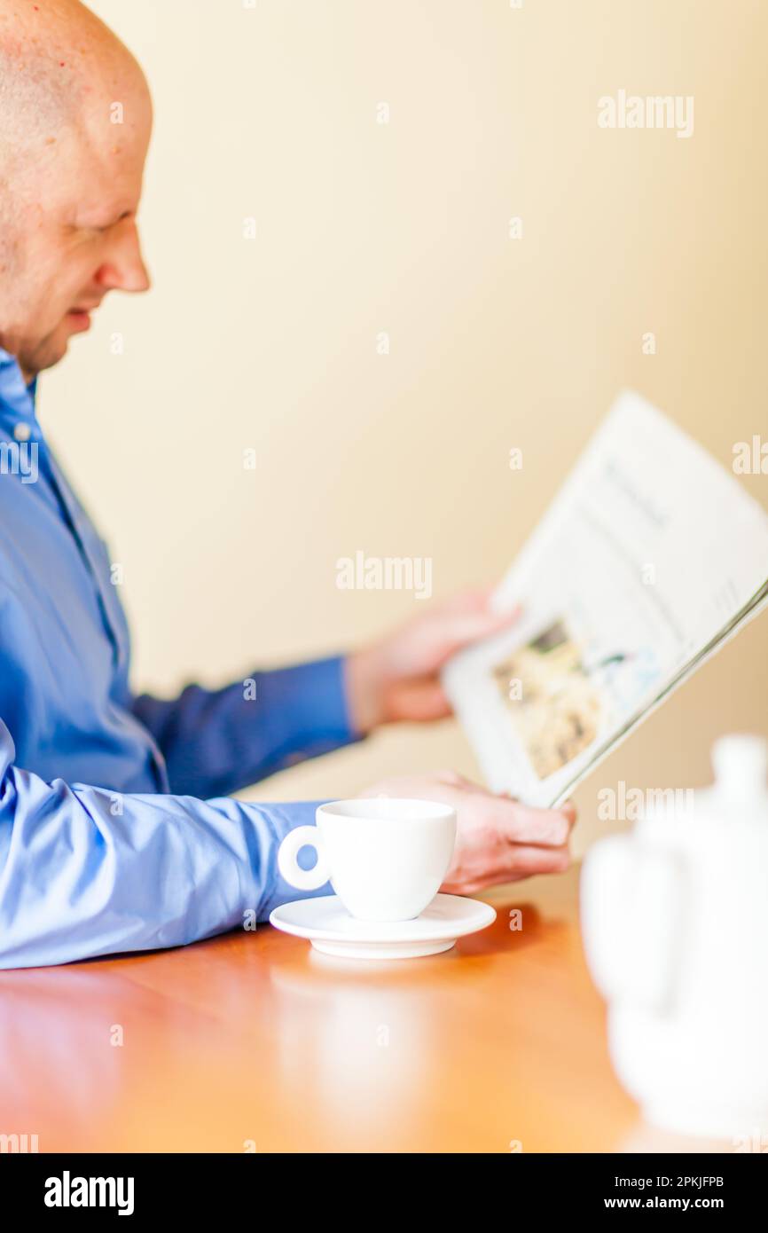 Un Best Ager es beber café y leer un periódico. Foto de stock