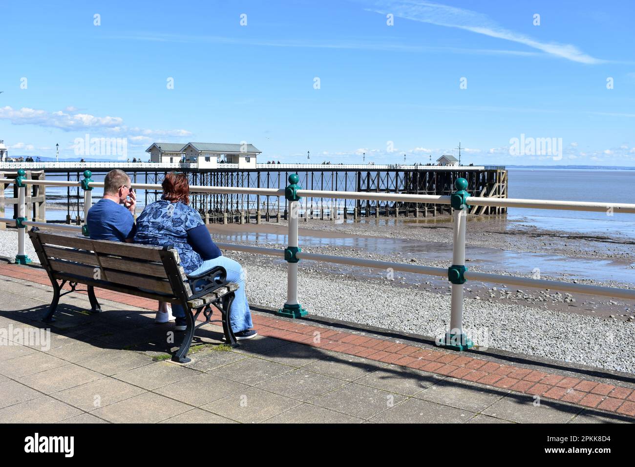 Pareja sentada en un banco cerca del muelle de Penarth, Penarth, Gales Foto de stock