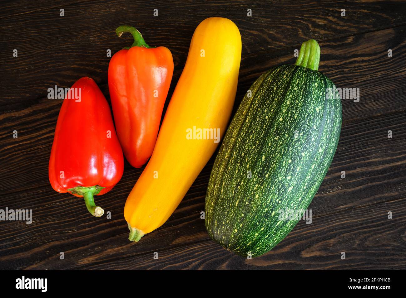 Médula vegetal y pimienta dulce en la mesa de madera oscura, plana. Vista superior de calabacín fresco en tablones vintage, conjunto de alimentos orgánicos. Concepto de squash Foto de stock