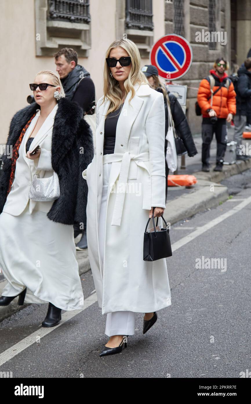 MILÁN, ITALIA - 26 DE FEBRERO de 2023: Mujer con abrigo y pantalón blanco antes del desfile de Giorgio Armani, estilo callejero de la Semana de la Moda de Milán Foto de stock
