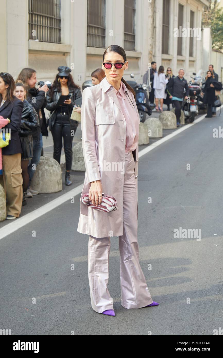 MILÁN, ITALIA - 23 DE FEBRERO de 2023: Mujer con chaqueta rosa claro, pantalones y zapatos morados antes del desfile de Genny, estilo callejero de la Semana de la Moda de Milán Foto de stock