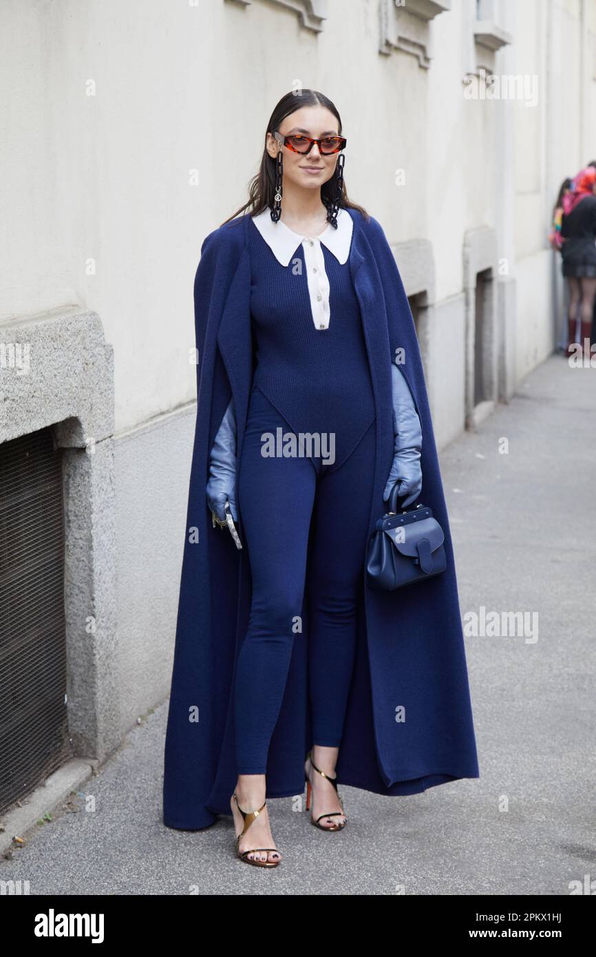 MILÁN, ITALIA - 23 DE FEBRERO de 2023: Mujer con abrigo azul y mono antes del desfile de Genny, estilo callejero de la Semana de la Moda de Milán Foto de stock