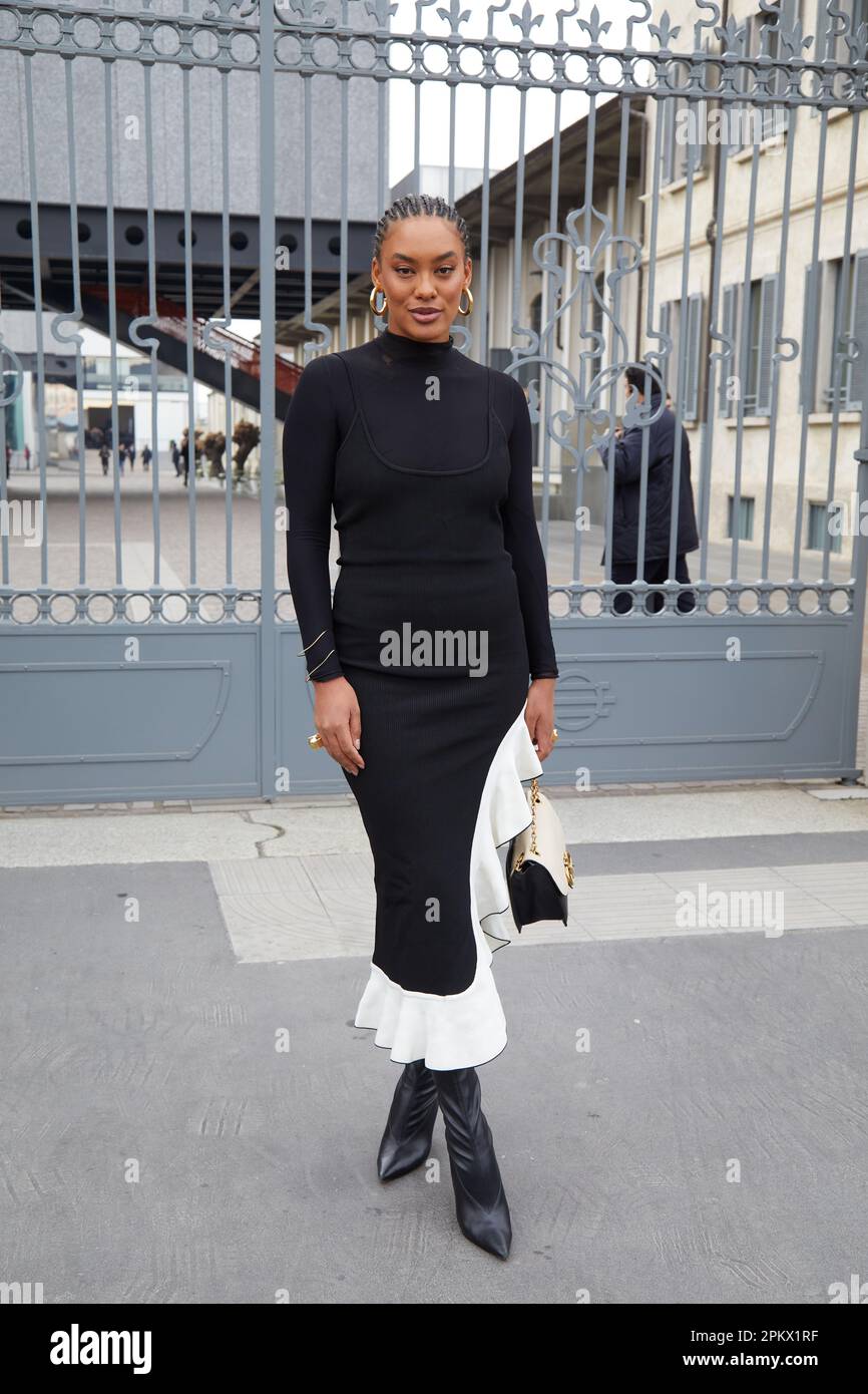 MILÁN, ITALIA - 23 DE FEBRERO de 2023: Mujer con vestido blanco y negro y botas puntiagudas antes del desfile de Prada, estilo callejero de la Semana de la Moda de Milán Foto de stock