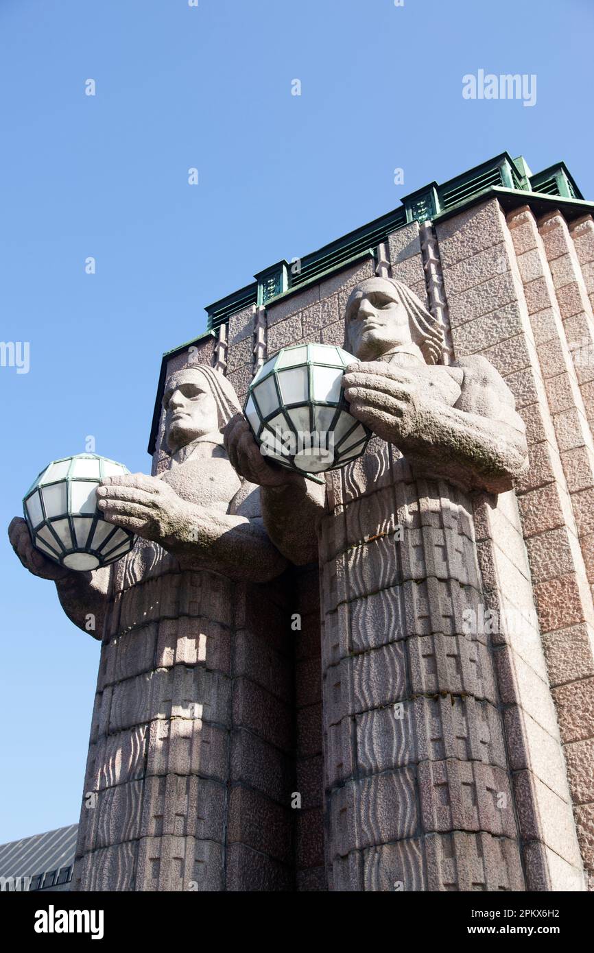 Finlandia, Helsinki, estación de tren principal, estatuas góticas de gigantes míticos o dioses sosteniendo lámparas esféricas, dando la bienvenida a los viajeros. Foto de stock