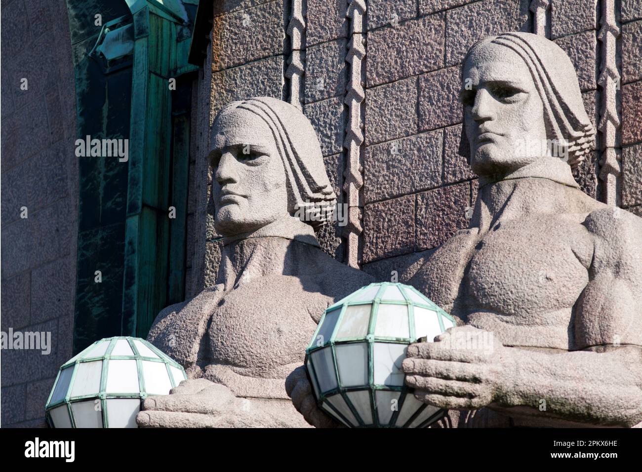 Finlandia, Helsinki, estación de tren principal, estatuas góticas de gigantes míticos o dioses sosteniendo lámparas esféricas, dando la bienvenida a los viajeros. Foto de stock