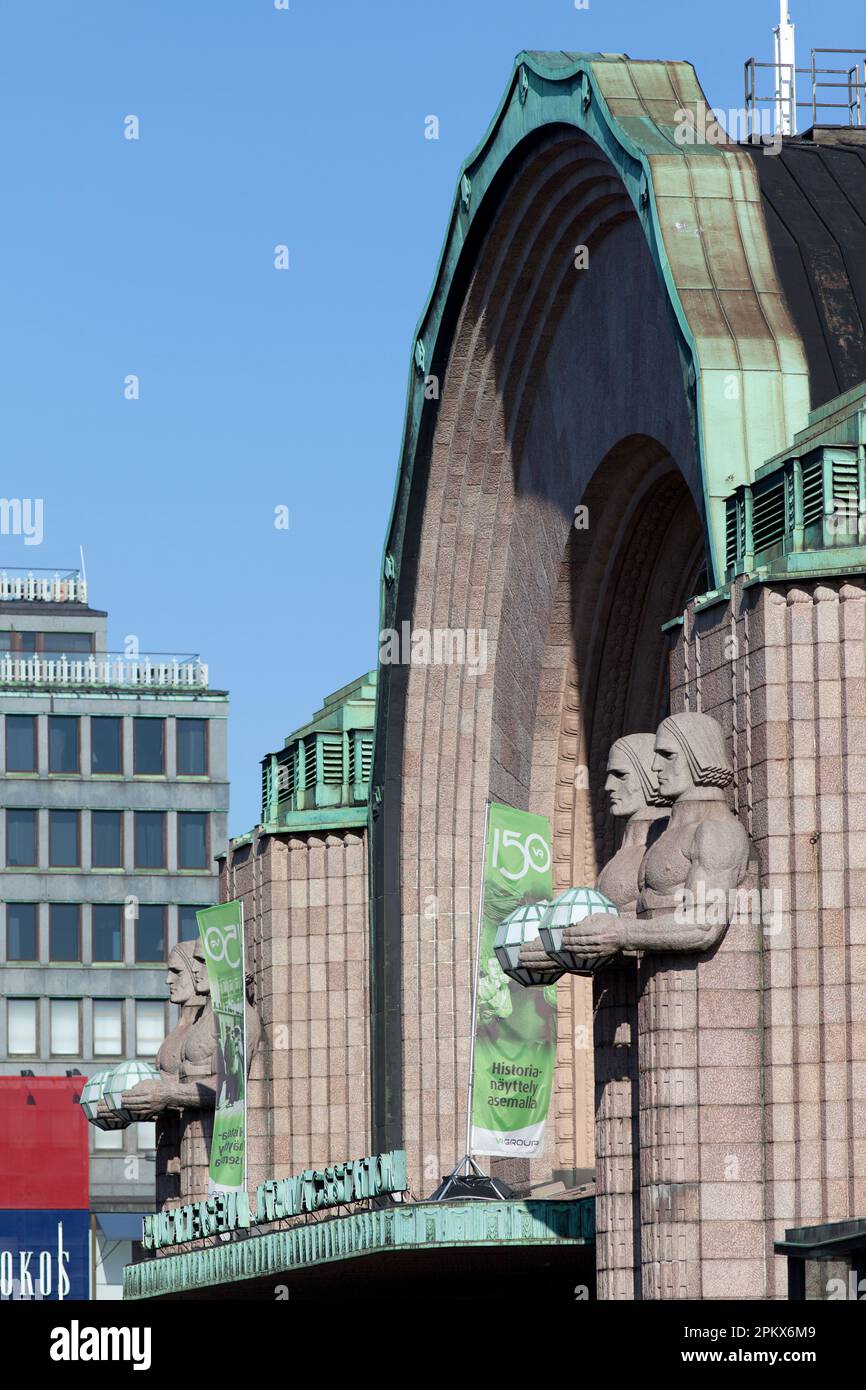 Finlandia, Helsinki, estación de tren principal, estatuas góticas de gigantes míticos o dioses sosteniendo lámparas esféricas, dando la bienvenida a los viajeros. Foto de stock