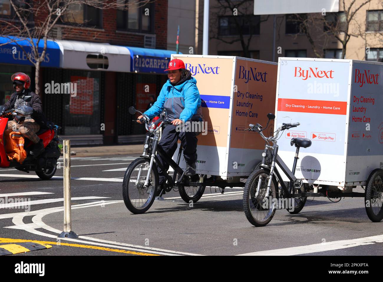 Un mensajero de bicicleta de entrega de lavandería y limpieza en seco ByNext en un triciclo de carga eléctrico de asistencia a pedales, bicicleta de carga en la ciudad de Nueva York. Foto de stock