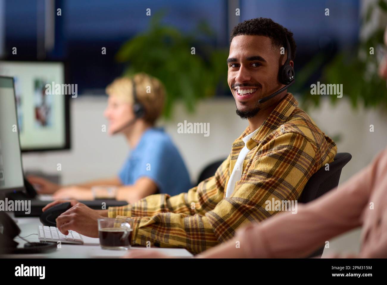 Retrato del equipo de negocios con auriculares que trabajan hasta tarde en el centro de atención al cliente Foto de stock