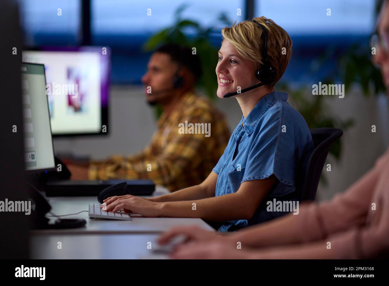El equipo empresarial lleva auriculares trabajando hasta tarde en el centro de atención al cliente Foto de stock