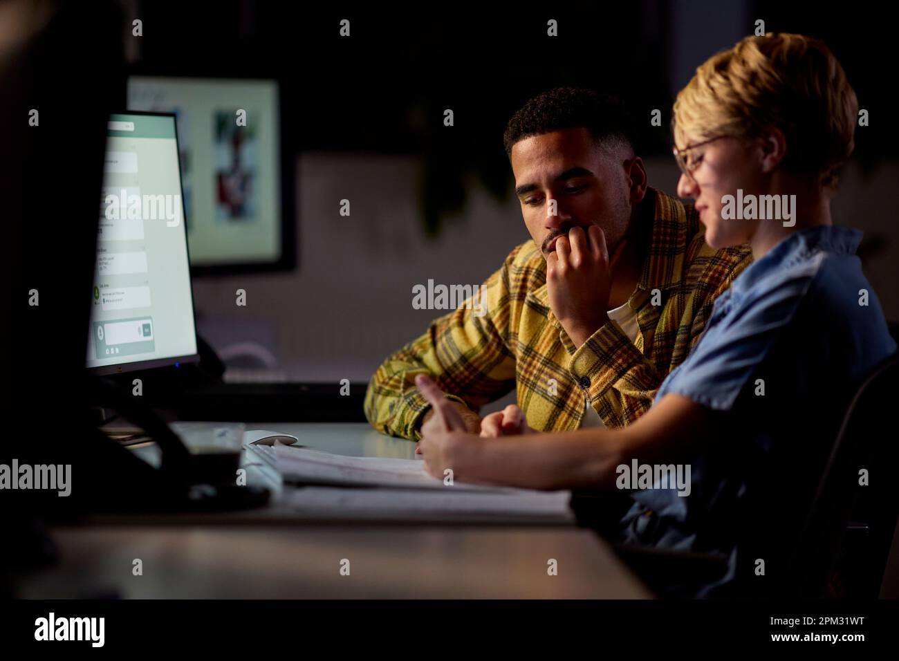 Dos colegas de negocios en los escritorios de la oficina que trabajan tarde en el proyecto juntos Foto de stock