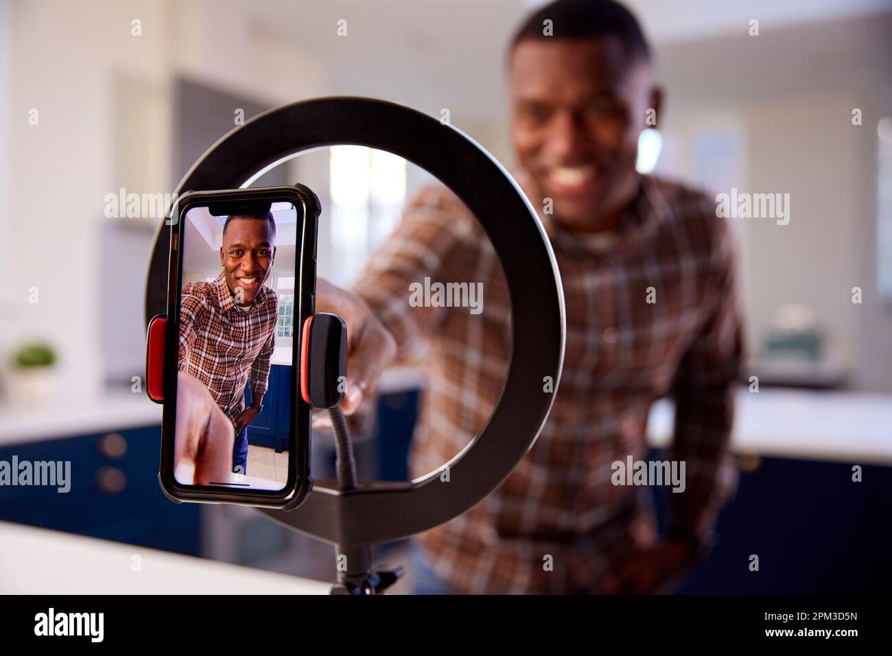 Hombre en casa Grabación de vídeo para subir a las redes sociales en el teléfono móvil Foto de stock