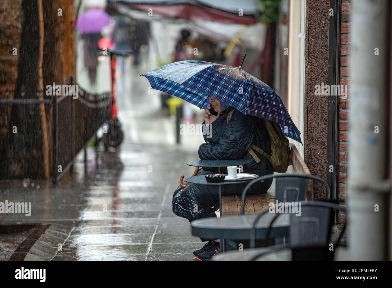 Una mujer joven con un paraguas en una chaqueta de lluvia usa una
