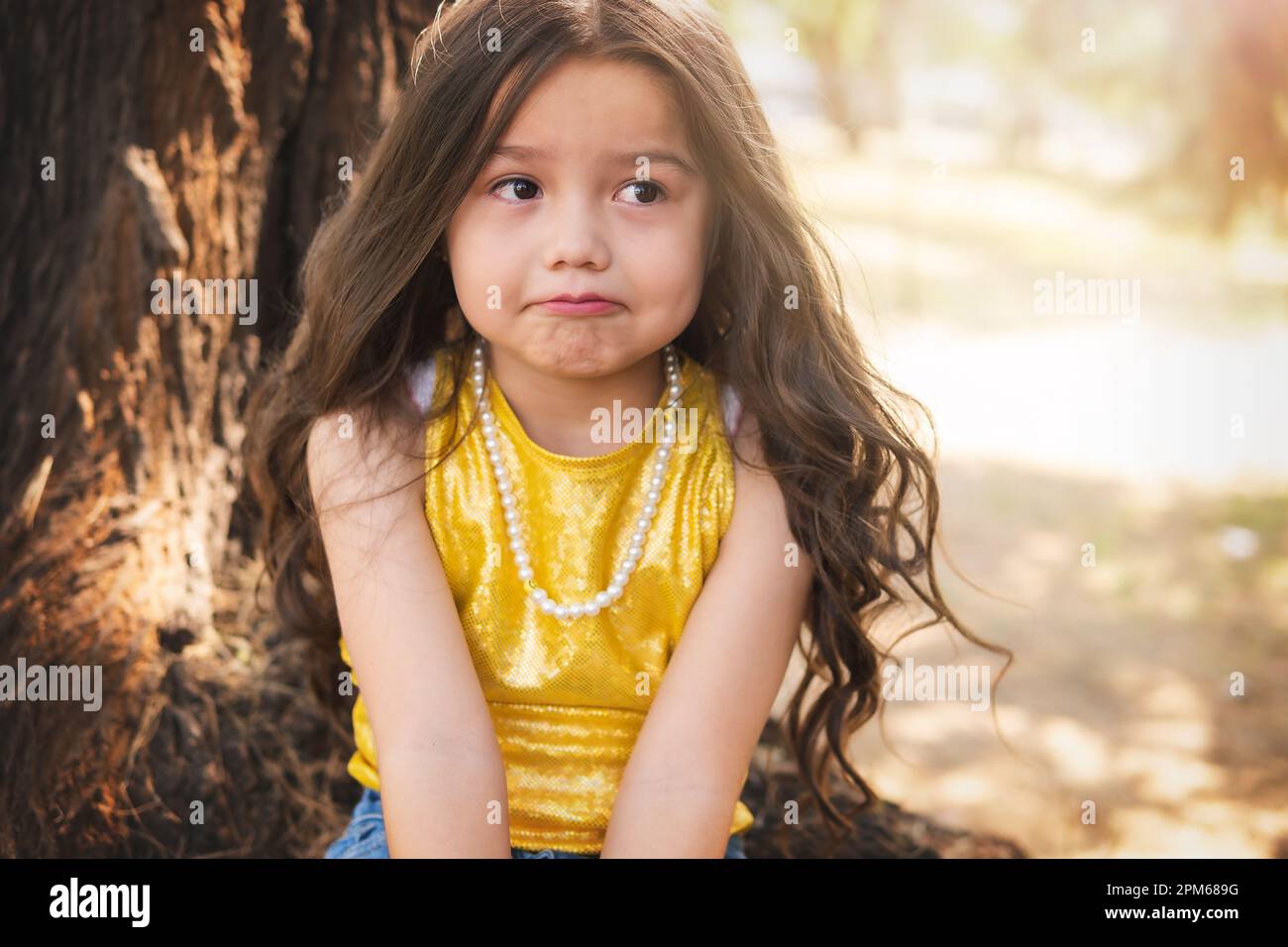 Expresión dudosa de una niña, hermosa chica rubia, tema del día de los niños. Foto de stock