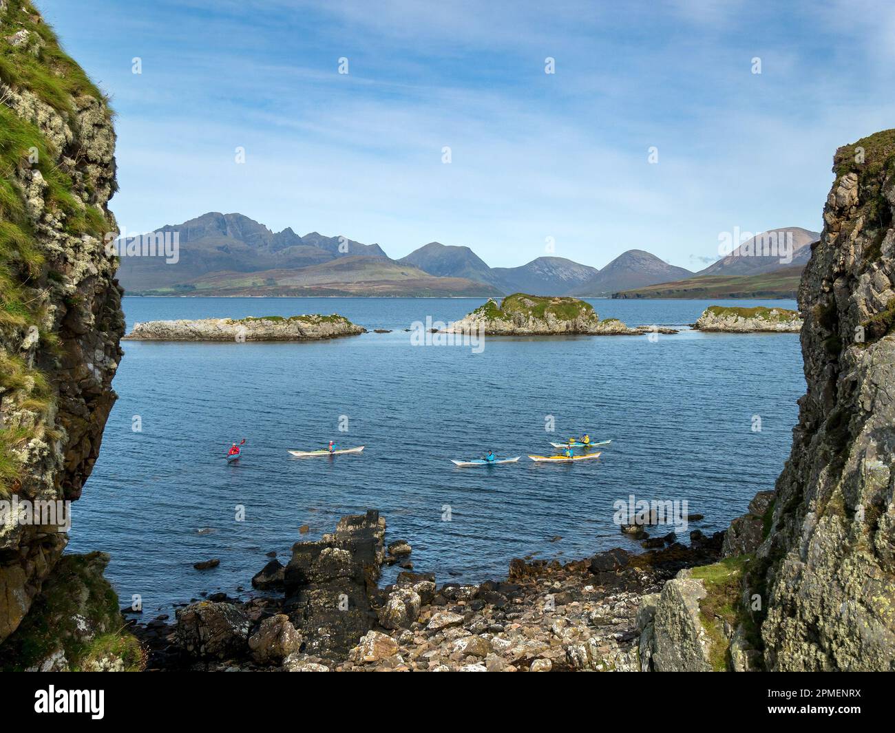 Kayakistas de mar por las islas de Eilean Ruairidh en el lago Eishort con las montañas Cuillin más allá, como se ve desde Tokavaig, Isla de Skye, Escocia, Reino Unido Foto de stock