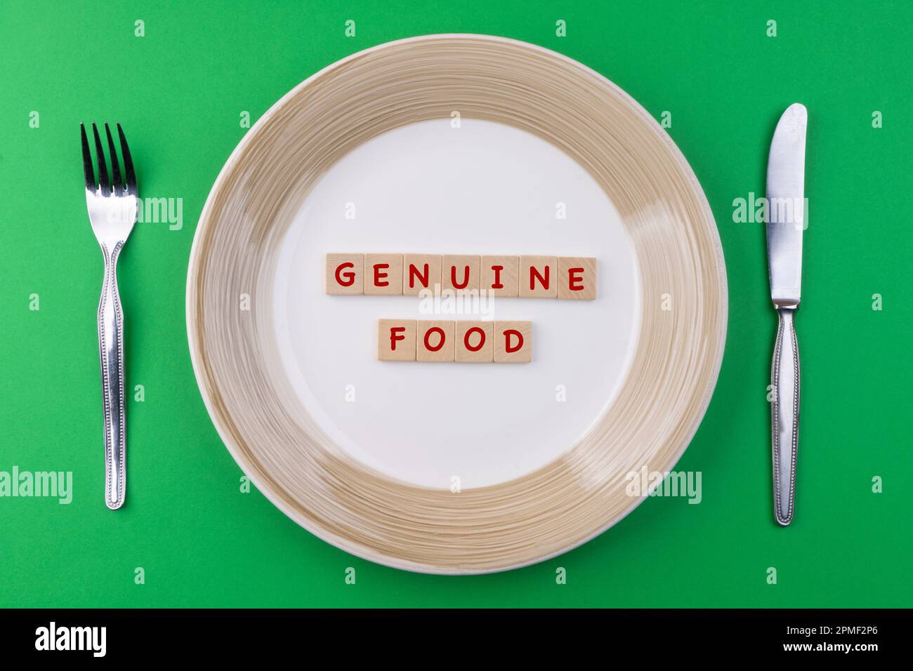 Cubiertos y un plato con la inscripción Genuine Food Foto de stock