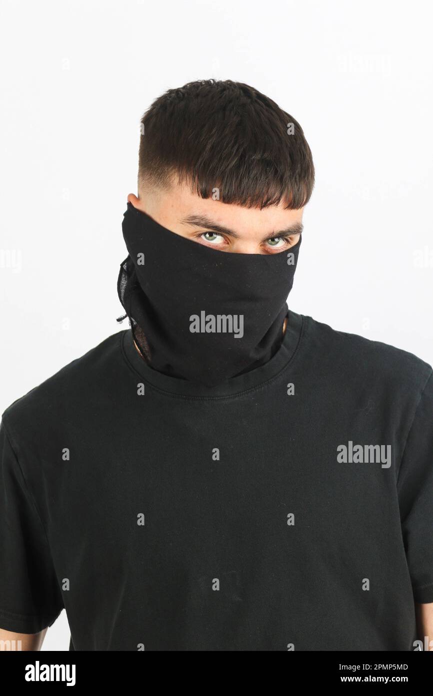 Adolescente que lleva una máscara negra contra un fondo blanco Foto de stock