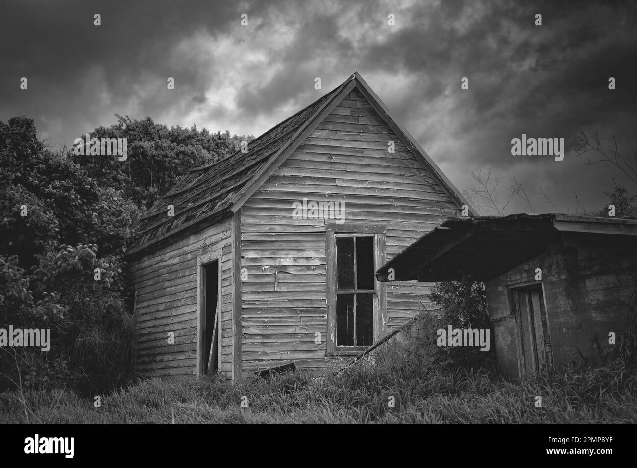 Imagen en blanco y negro de una casa vieja y espeluznante abandonada bajo nubes meteorológicas amenazantes en el este de Washington, EE.UU Foto de stock
