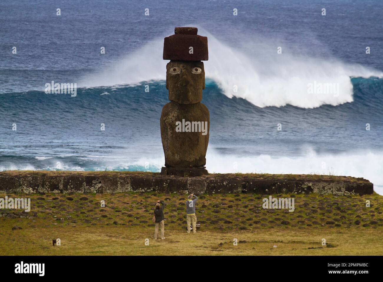 Los turistas se ponga delante de un moai. Foto de stock