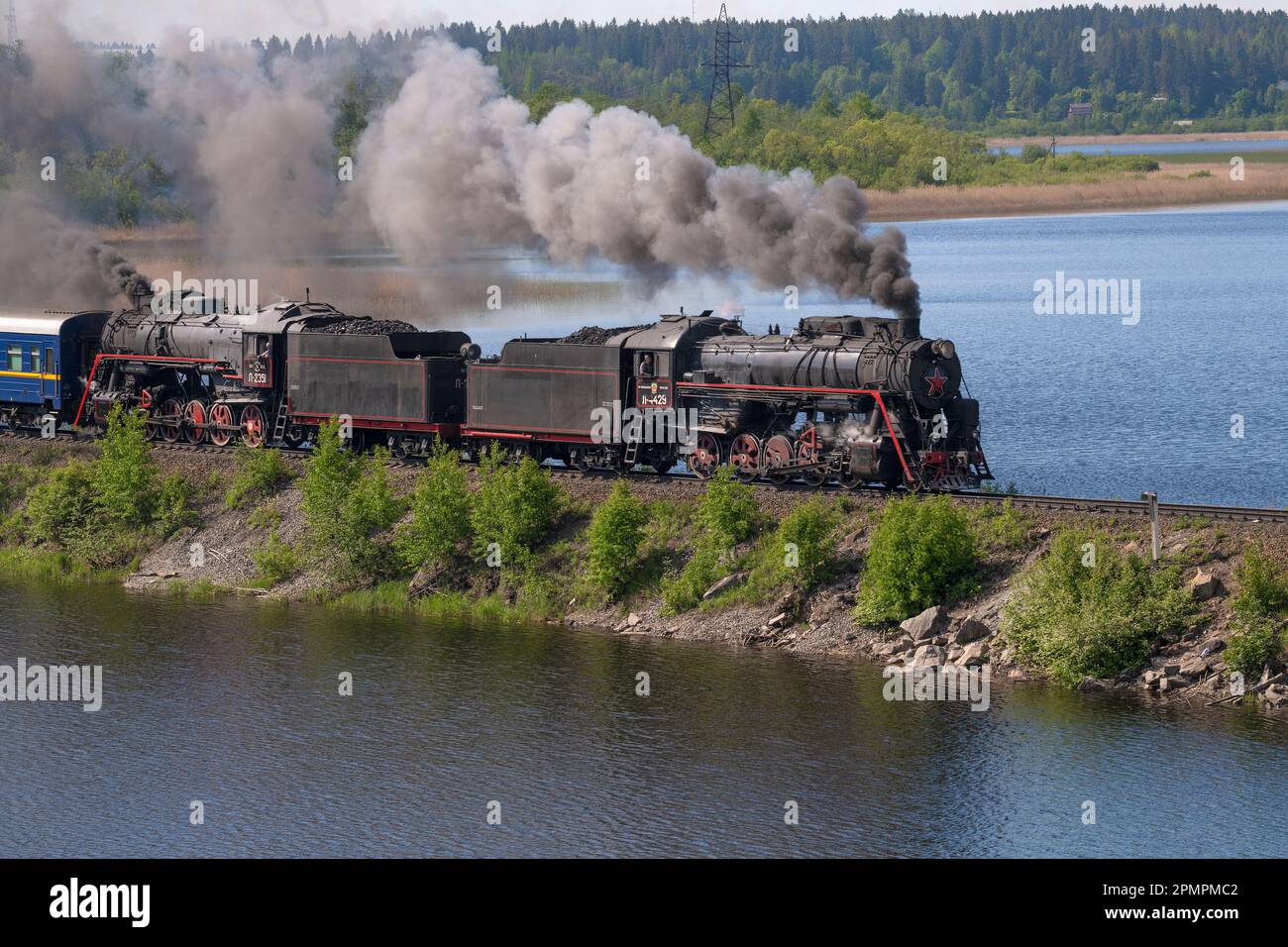 HELULYA, RUSIA - 11 DE JUNIO de 2022: Dos antiguas locomotoras de vapor soviéticas de la serie 'L' en movimiento en la presa del lago Karmalanjärvi en un soleado junio Foto de stock