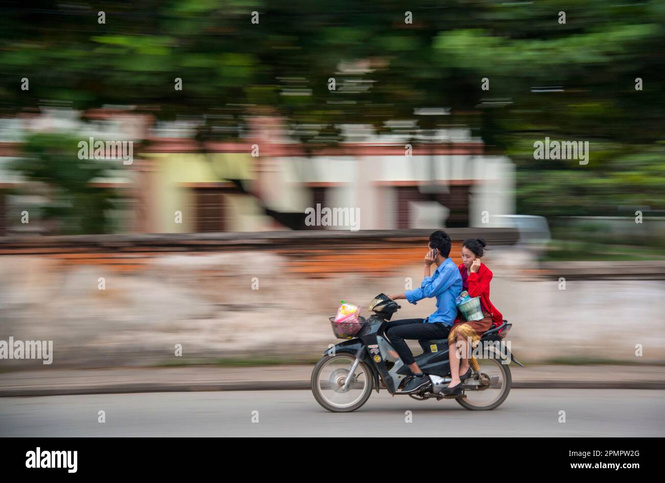 Un motociclista y su jinete hablan por teléfono celular mientras están en marcha. Foto de stock