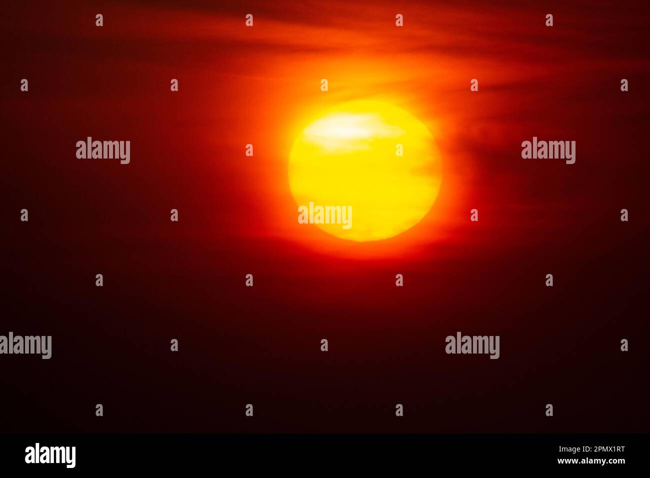 Sumérgete en el momento cautivador de una espectacular puesta de sol con cielos naranjas ardientes y un sol radiante Foto de stock