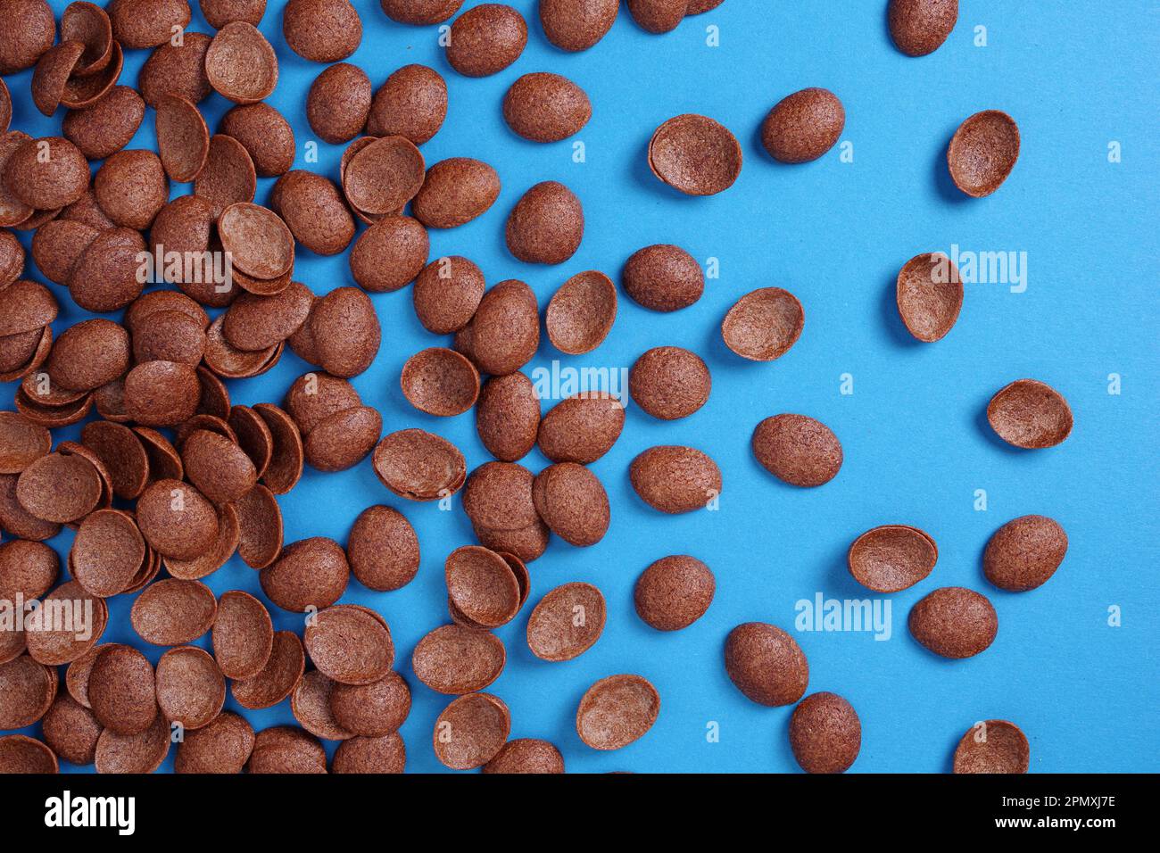 Cereales de chocolate como fondo en azul. Copos de maíz esmaltados en forma de conchas. Vista superior Foto de stock