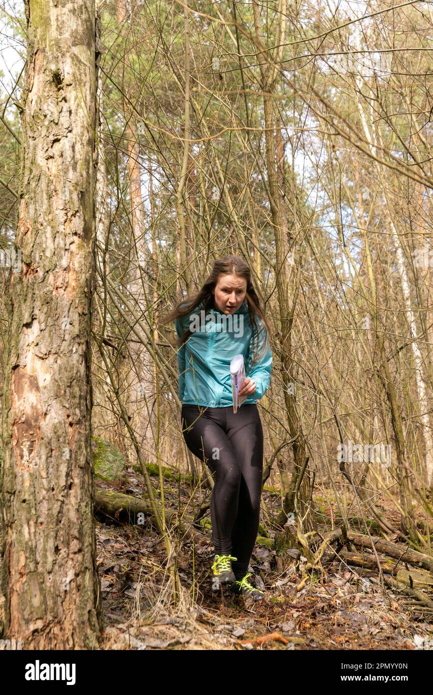 Grodno, Bielorrusia - 25 de marzo de 2023: Mujer joven caucásica fuerte  vistiendo ropa deportiva corriendo a través de un bosque durante el  ejercicio en orientación al aire libre Gro Fotografía de stock - Alamy