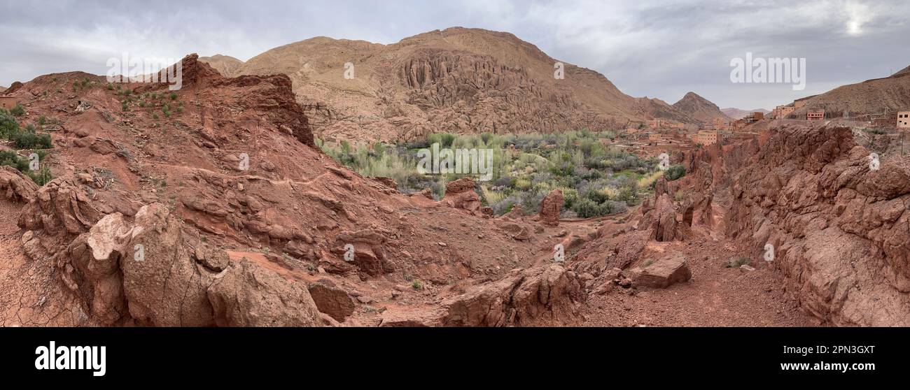 Marruecos, África: Montañas rojas y suculentas con uno de los impresionantes pueblos de arcilla en el verde valle del Dades cerca de Boumalne Dades y Dades Gorge Foto de stock