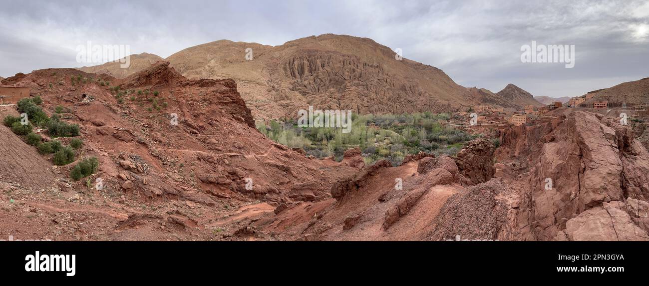 Marruecos, África: Montañas rojas y suculentas con uno de los impresionantes pueblos de arcilla en el verde valle del Dades cerca de Boumalne Dades y Dades Gorge Foto de stock