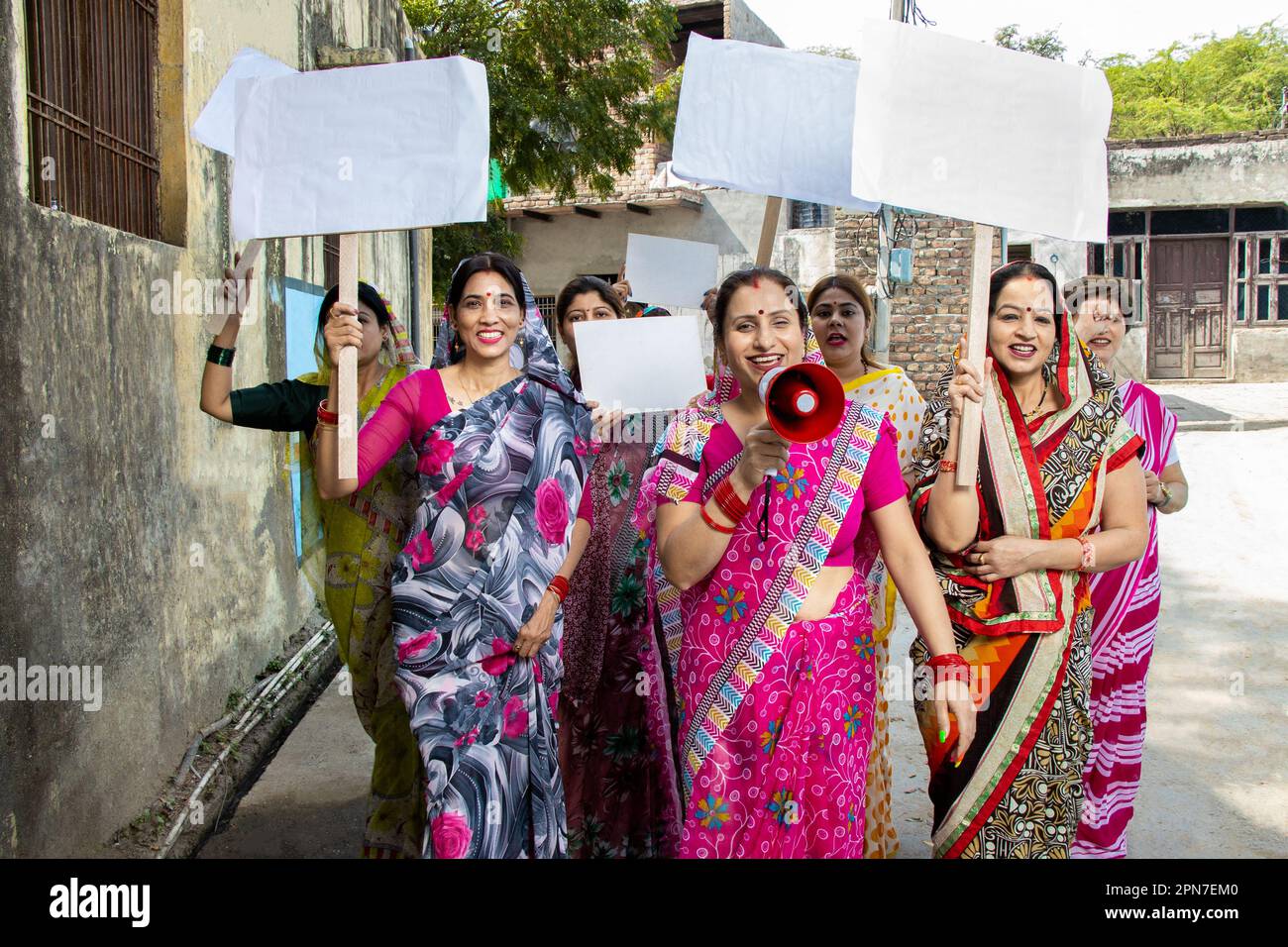 Grupo de mujer india tradicional sosteniendo cartel de cartón en blanco protestando gritando en megáfono. Activista femenina protestando con megáfono durante A Foto de stock