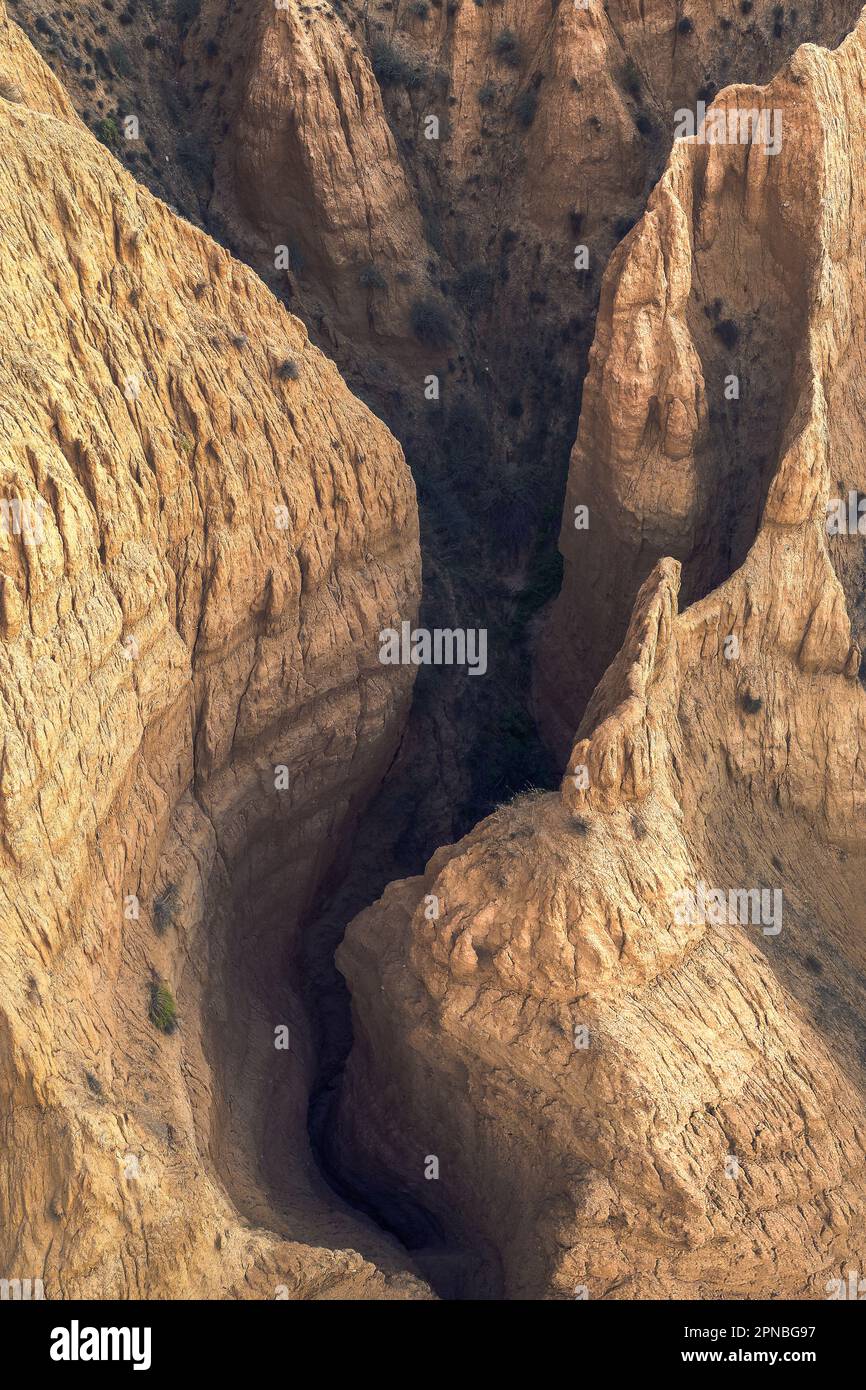 Vista aérea de la formación rocosa áspera con cañón profundo y oscuro en el medio mientras que desprovisto de vegetación y habitación en la luz del día Foto de stock