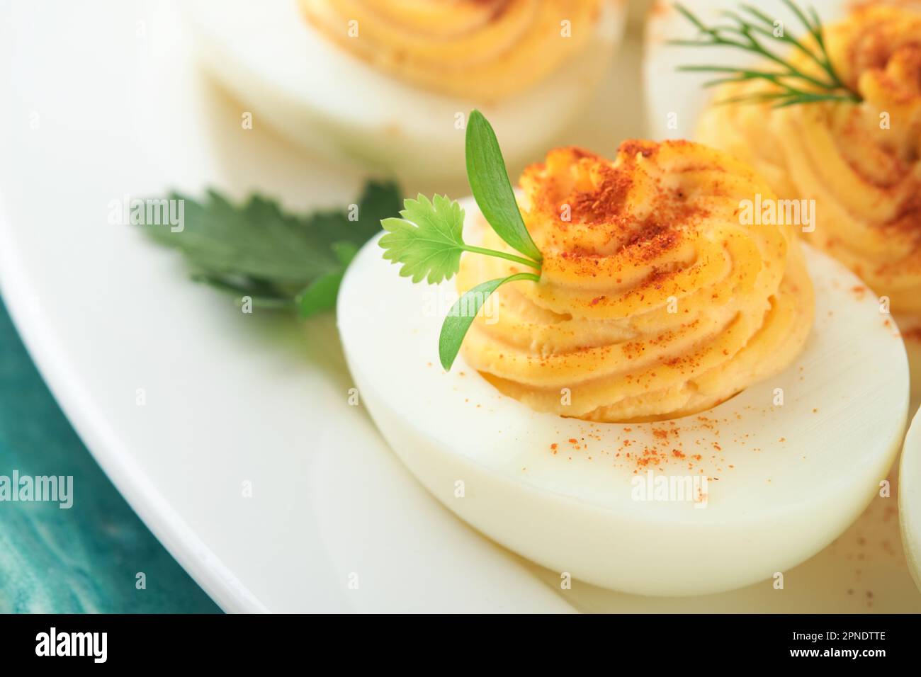 Huevos rellenos o diabólicos con pimentón y perejil en plato azul para mesa  de pascua. Plato tradicional para Pascua. Comida saludable de la dieta para  el desayuno. Vista superior Fotografía de stock 