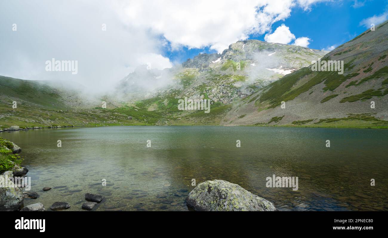 Majestuoso lago de montaña azul con nubes nebulosas Foto de stock