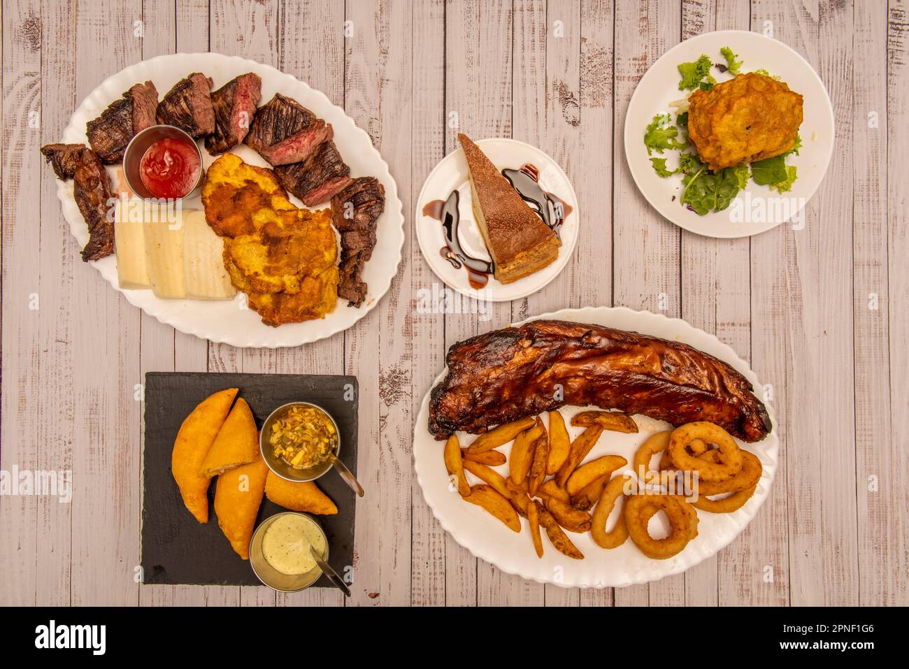 Una combinación de platos de gastronomía colombiana con carnes cocinadas a carbón, empanadas de maíz con salsas de chile y una patata rellena Foto de stock