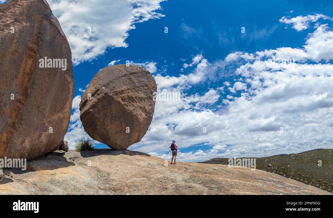 Australia, Queensland, Girraween National Park, mujer de pie junto a una gran roca durante la caminata en el desierto Foto de stock