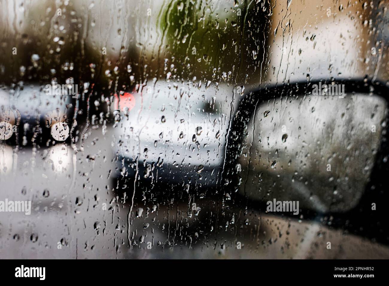 espejo derecho del coche bajo la lluvia, mala visibilidad en la carretera. Foto de stock