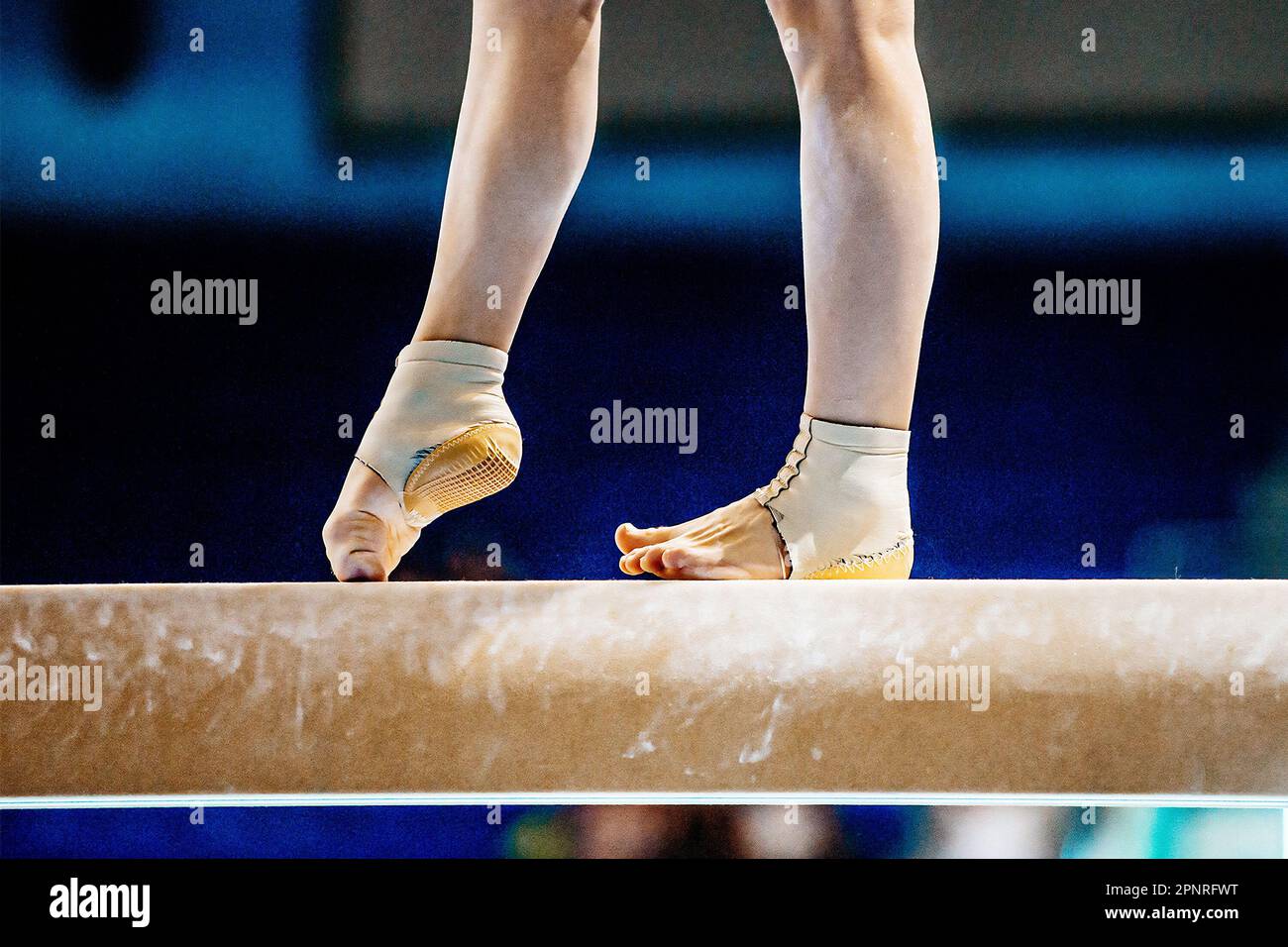 piernas de primer plano gimnasta femenina paso en la viga de equilibrio en gimnasia, apoyo de tobillo de neopreno ajustado con copa de talón Foto de stock