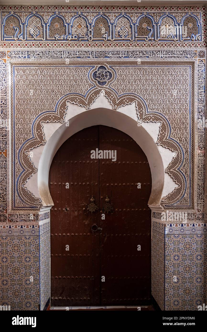 Puerta de entrada a una pequeña mezquita decorada con adornos árabes en la medina de Marrakech. Foto de stock
