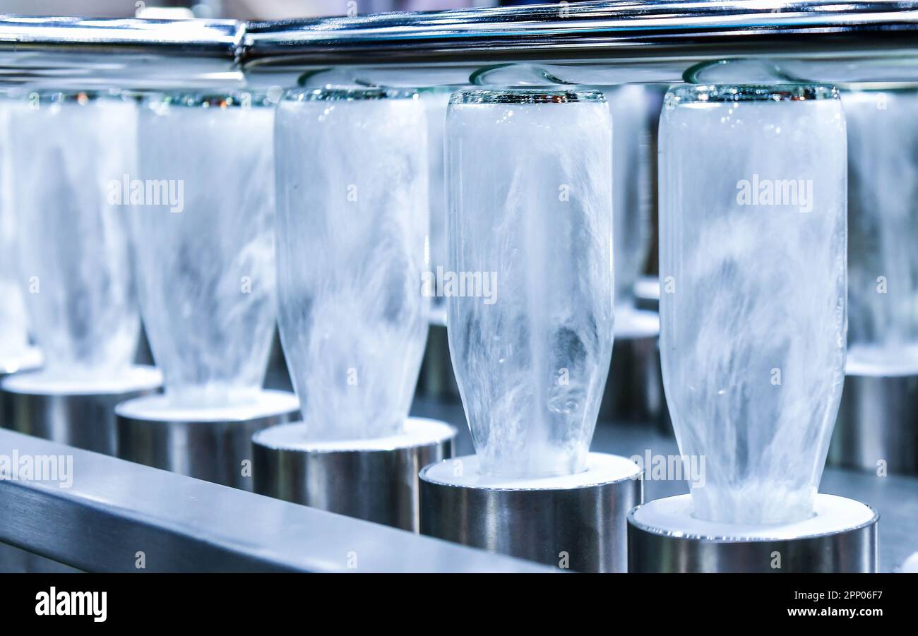 Botellas de limpieza botellas de vidrio para productos de bebidas en proceso por agua caliente en la máquina automática en la fabricación Foto de stock