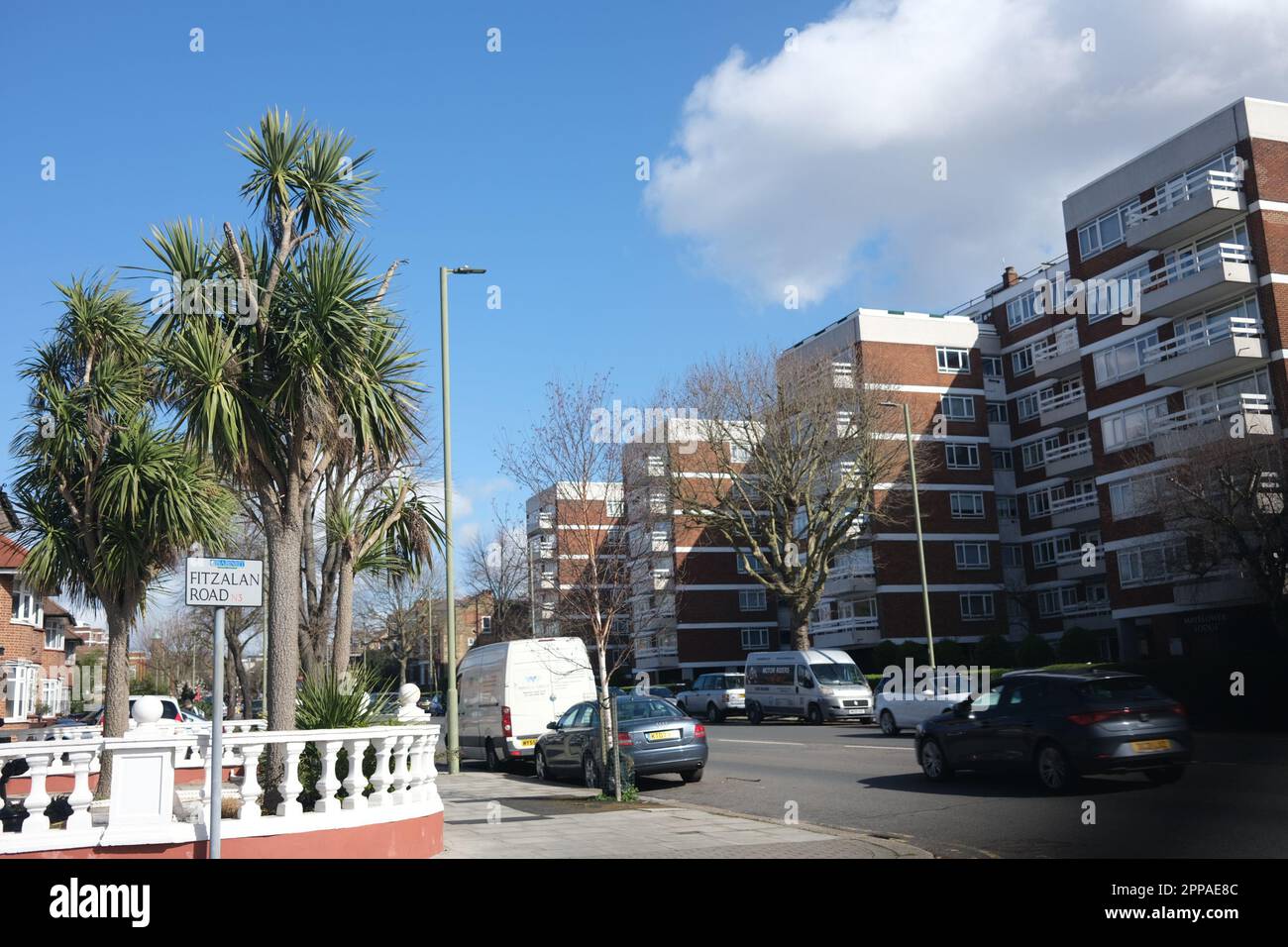 Apartamentos residenciales inteligentes en una zona de lujo de Finchley Norte de Londres en marzo de 2023 con coches, árboles y vallas ornamentales, con un telón de fondo soleado Foto de stock