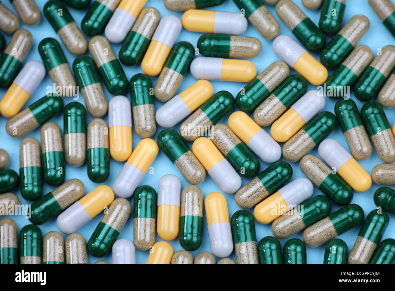 Píldoras en cápsulas, variación de la medicación dispersa sobre fondo azul. Farmacia, antibióticos, vitaminas Foto de stock