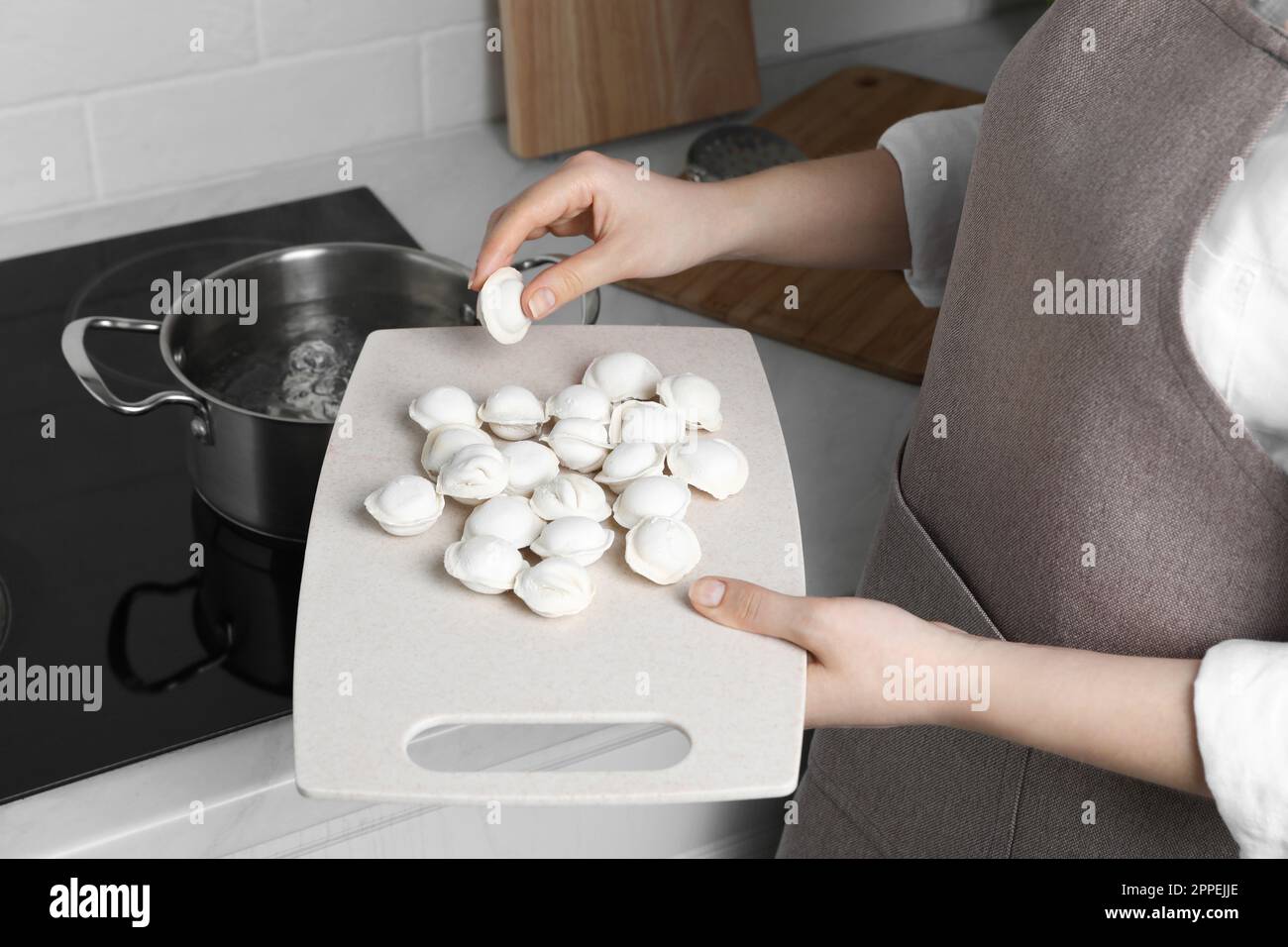 Mujer que pone albóndigas congeladas en una cacerola con agua hirviendo en  la estufa en la cocina, primer plano Fotografía de stock - Alamy