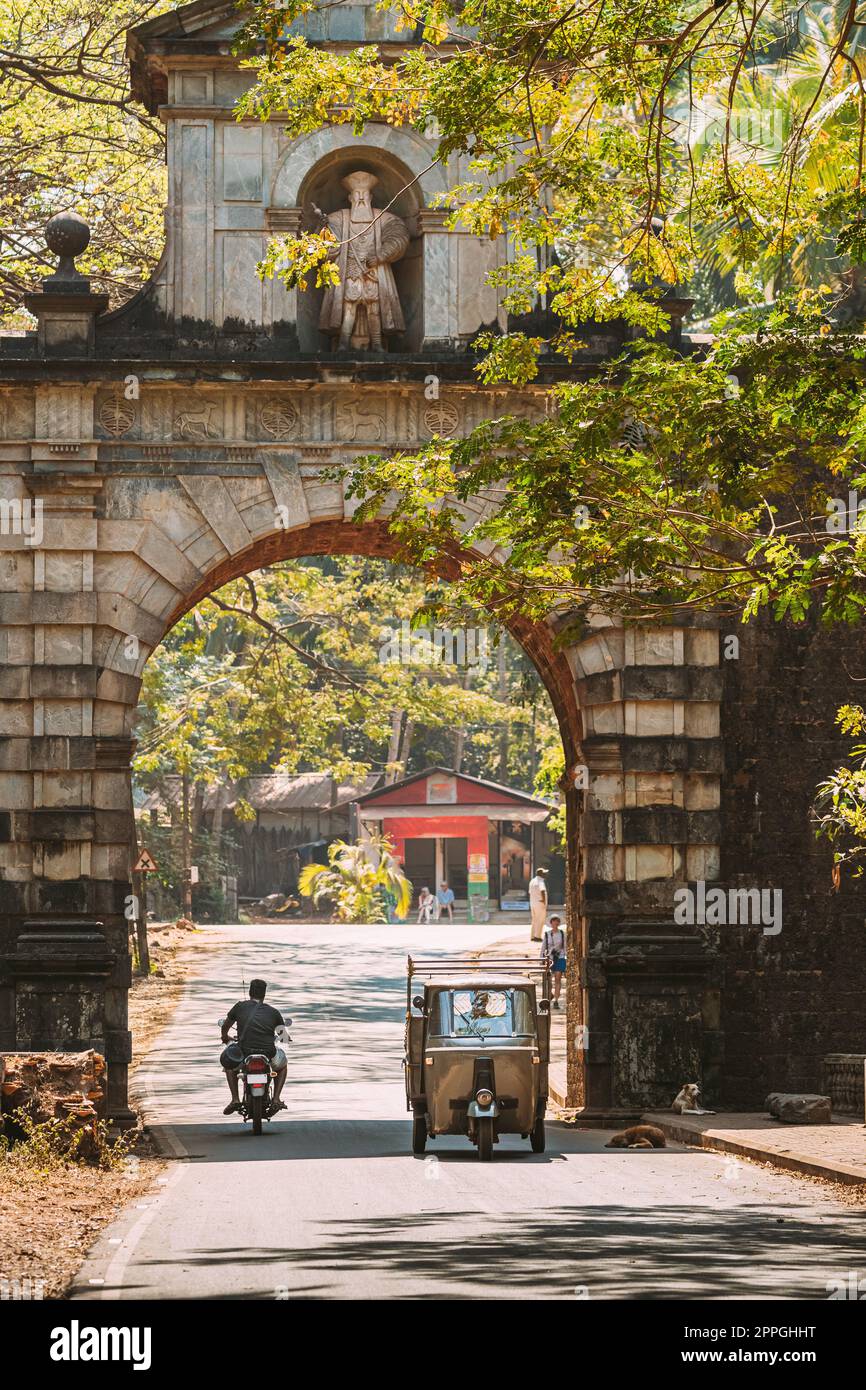 Old Goa, India. Auto Rickshaw o Tuk-tuk moviéndose a través del antiguo arco de Viceroyâ€™. Famoso Vasco Da Gama Puerta punto de referencia y Patrimonio Histórico.Calle en día soleado Foto de stock