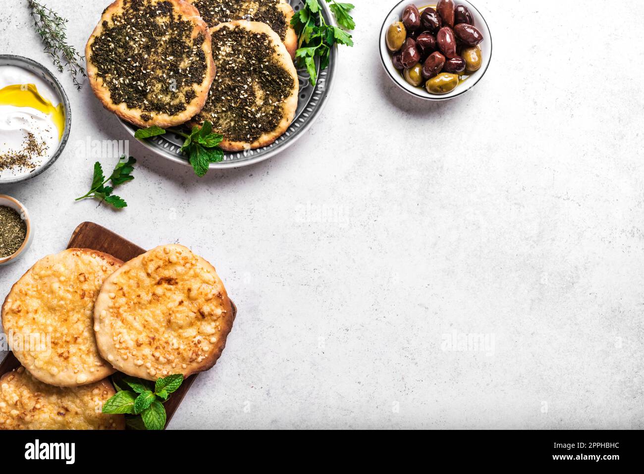 Desayuno árabe, yogur labneh, pan de manakeesh o pita con queso y zaatar en mesa blanca, espacio de copia. Comida de Oriente Medio, cocina árabe. Foto de stock