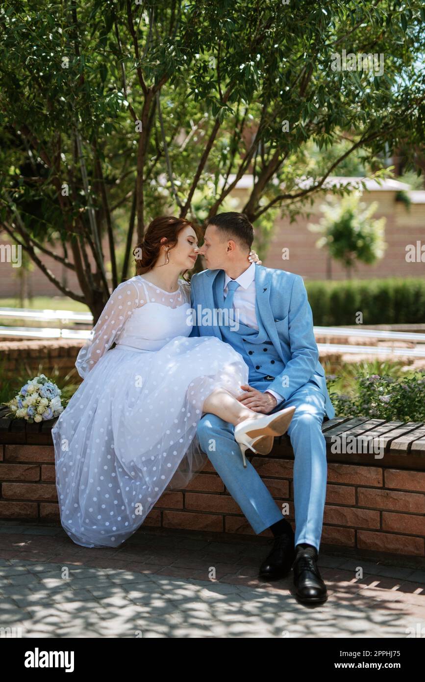 taller inversión desierto novia en un vestido de novia ligero con un ramo junto al novio en un traje  azul Fotografía de stock - Alamy